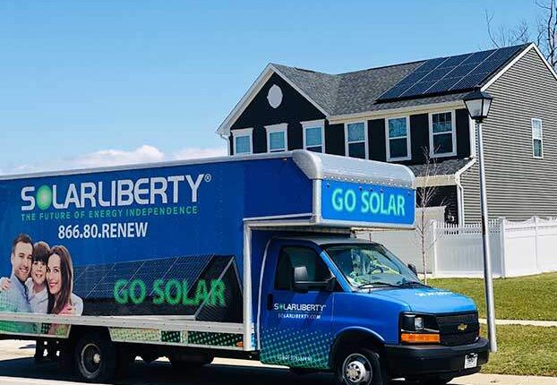Company van in front of house with solar panels on roof